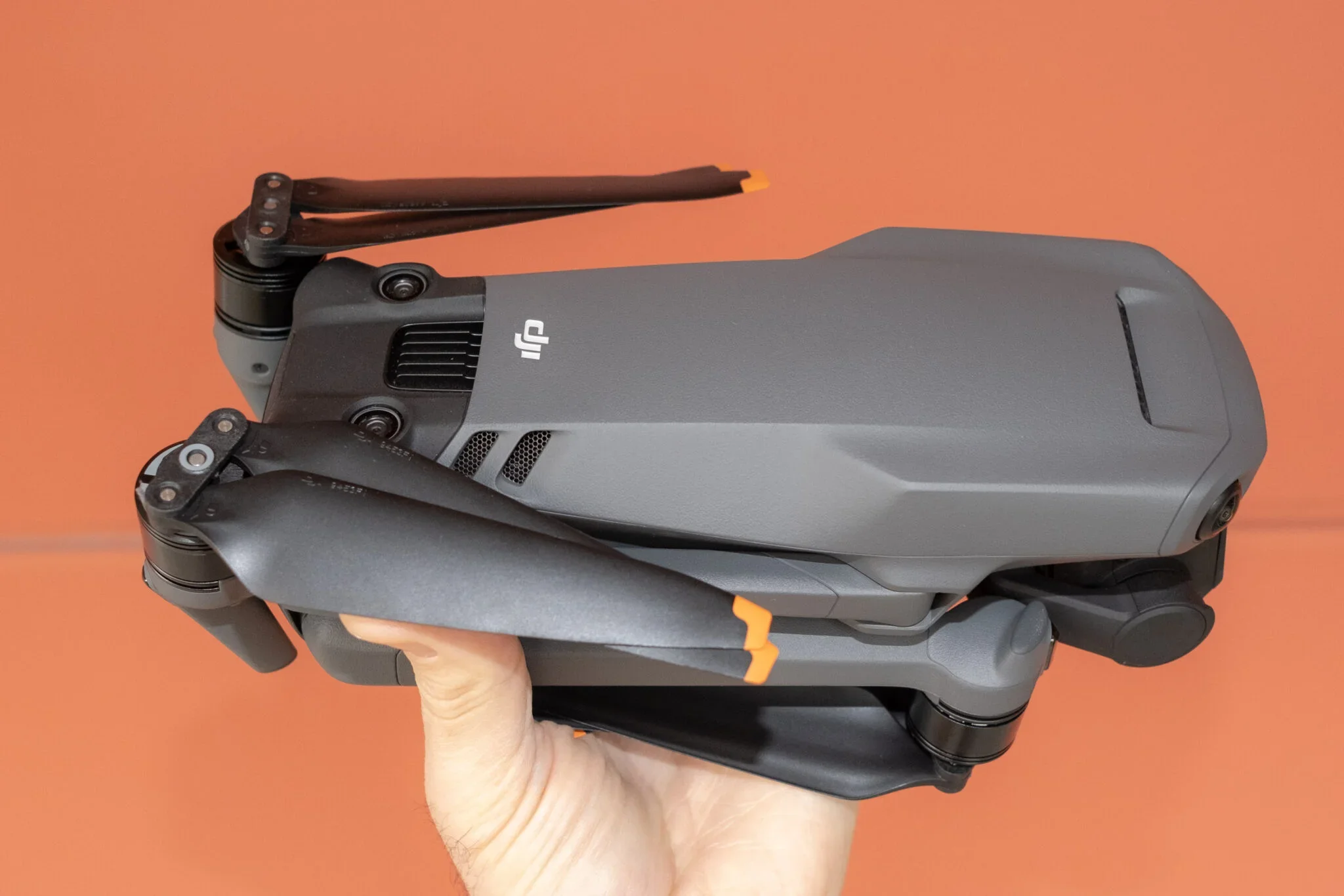 DJI Mavic 3 drone in a hand on an orange background